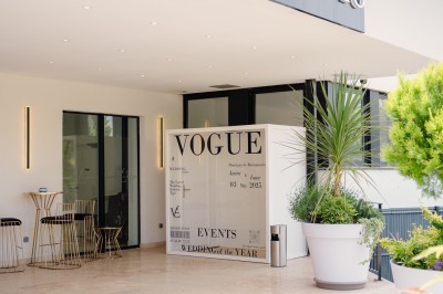 Parking vide entouré d'arbres et de bâtiments sous un ciel bleu avec quelques nuages.