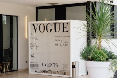 Parking vide entouré d'arbres et de bâtiments sous un ciel bleu avec quelques nuages.