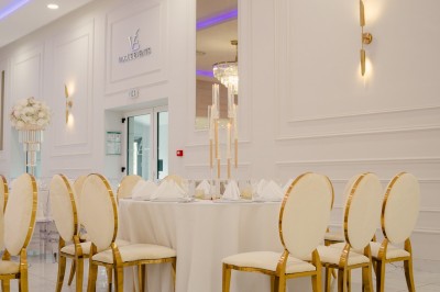 Parking vide entouré d'arbres et de bâtiments sous un ciel bleu avec quelques nuages.