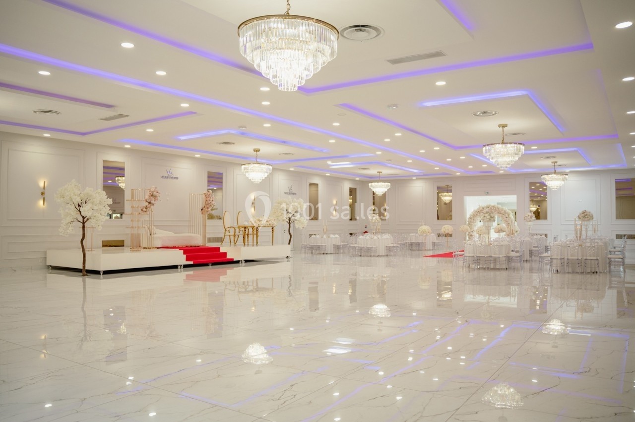 Salle de réception lumineuse avec sol en marbre, lustres élégants et décoration blanche et dorée.