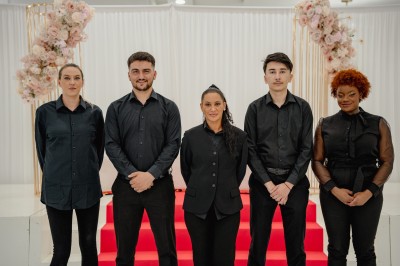 Parking vide entouré d'arbres et de bâtiments sous un ciel bleu avec quelques nuages.