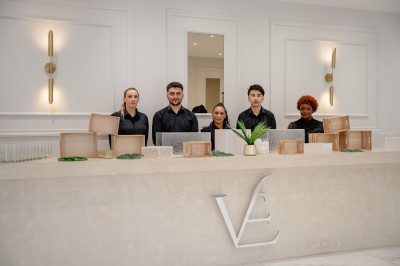 Parking vide entouré d'arbres et de bâtiments sous un ciel bleu avec quelques nuages.