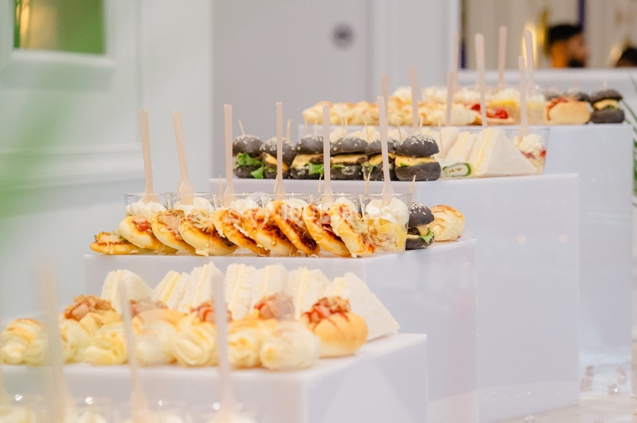 Plateaux de bouchées salées variées, incluant sandwichs, mini-burgers et amuse-bouches, présentés sur des supports blancs.