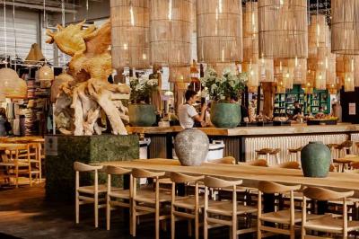 Sculpture de lion en pierre, table en bois sombre avec chandeliers noirs, vase bleu et décor rustique en arrière-plan.