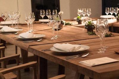 Tables en bois dressées avec des assiettes, des verres et des serviettes blanches dans une salle élégante.