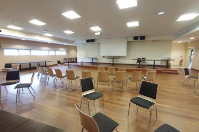 Espace intérieur lumineux avec des fauteuils en rotin, une table en bois et une décoration murale colorée.