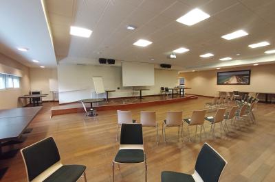 Espace intérieur lumineux avec des fauteuils en rotin, une table en bois et une décoration murale colorée.