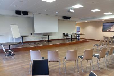 Espace intérieur lumineux avec des fauteuils en rotin, une table en bois et une décoration murale colorée.