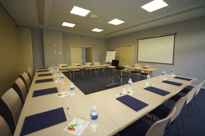 Espace intérieur lumineux avec des fauteuils en rotin, une table en bois et une décoration murale colorée.