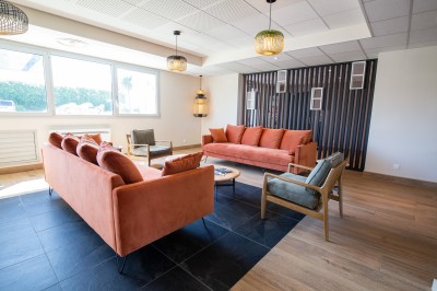 Espace intérieur lumineux avec des fauteuils en rotin, une table en bois et une décoration murale colorée.