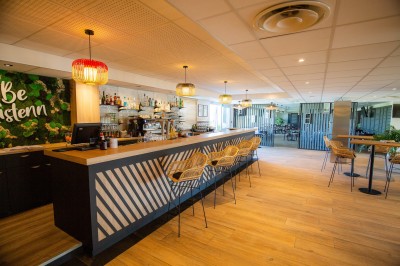 Espace intérieur lumineux avec des fauteuils en rotin, une table en bois et une décoration murale colorée.