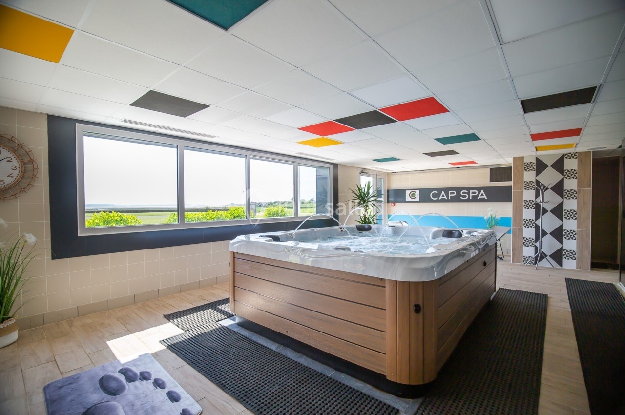 Jacuzzi moderne dans une pièce lumineuse avec vue sur la nature, décorée de carreaux et de panneaux colorés.