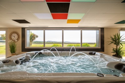 Espace intérieur lumineux avec des fauteuils en rotin, une table en bois et une décoration murale colorée.