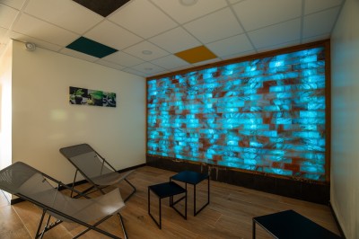 Espace intérieur lumineux avec des fauteuils en rotin, une table en bois et une décoration murale colorée.