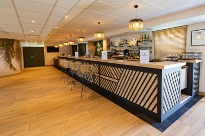Chambre d'hôtel moderne avec lit double, bureau, téléviseur mural, portant, et décoration murale à motifs floraux.