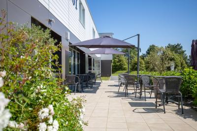 Chambre d'hôtel moderne avec lit double, bureau, téléviseur mural, portant, et décoration murale à motifs floraux.