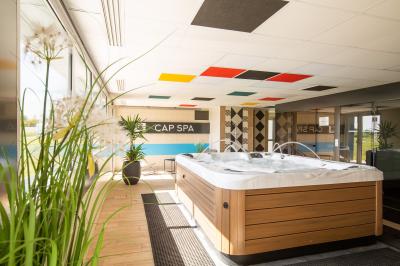 Chambre d'hôtel moderne avec lit double, bureau, téléviseur mural, portant, et décoration murale à motifs floraux.