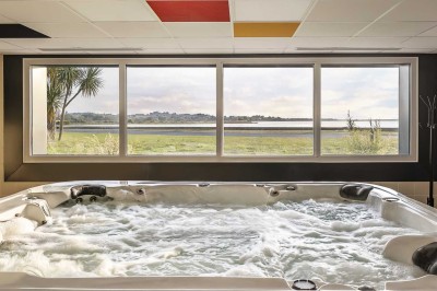 Chambre d'hôtel moderne avec lit double, bureau, téléviseur mural, portant, et décoration murale à motifs floraux.