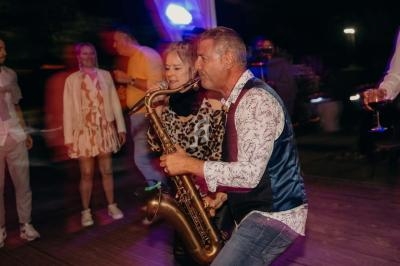 Un musicien joue du saxophone sur une scène, accompagné d'une chanteuse, devant un public en mouvement.