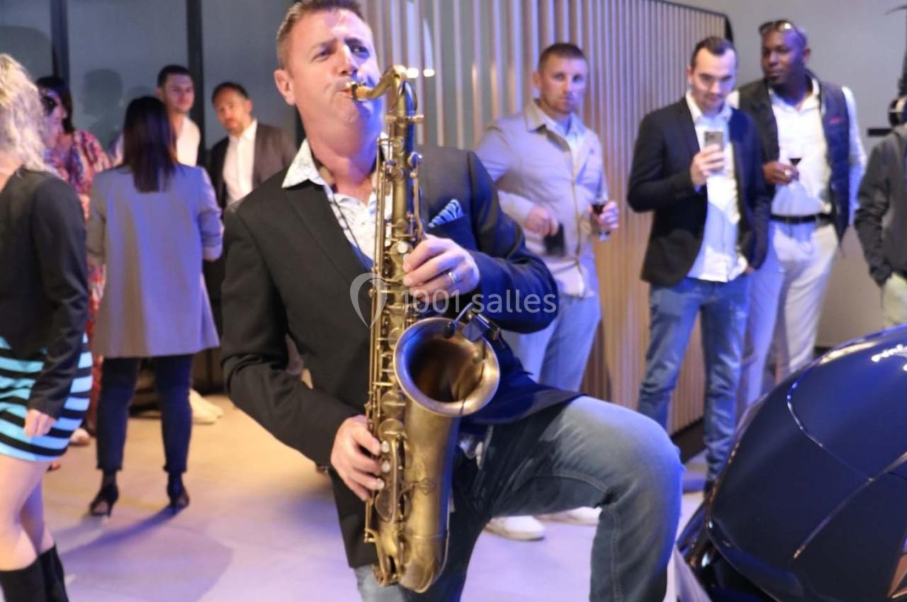 Un musicien joue du saxophone devant un public lors d'un événement en intérieur.