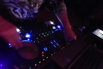 Deux personnes chantent et jouent de la musique en direct dans une ambiance nocturne éclairée par des lumières.