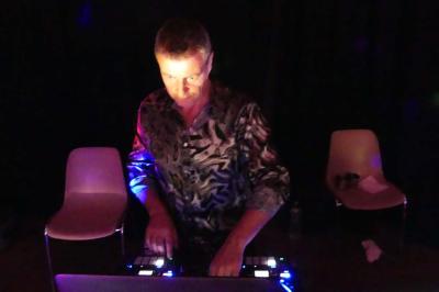 Deux personnes chantent et jouent de la musique en direct dans une ambiance nocturne éclairée par des lumières.