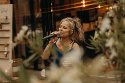 Deux personnes chantent et jouent de la musique en direct dans une ambiance nocturne éclairée par des lumières.