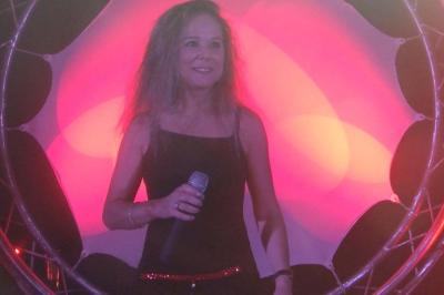 Deux personnes chantent et jouent de la musique en direct dans une ambiance nocturne éclairée par des lumières.