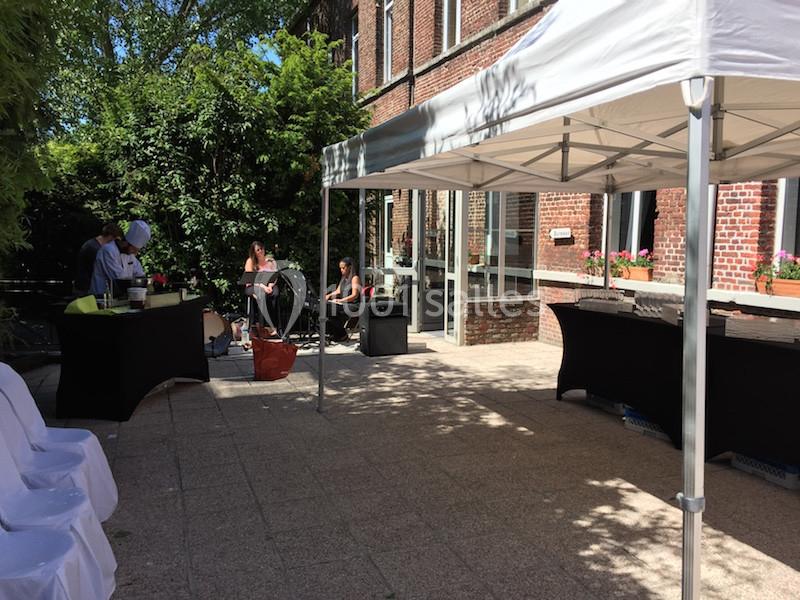 Terrasse ensoleillée avec des tables sous des tonnelles blanches, un musicien et une chanteuse en arrière-plan.