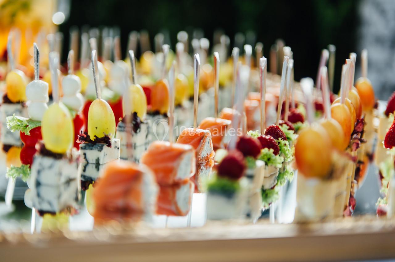 Assortiment de brochettes apéritives colorées avec fruits, fromages et saumon, disposées sur un plateau.