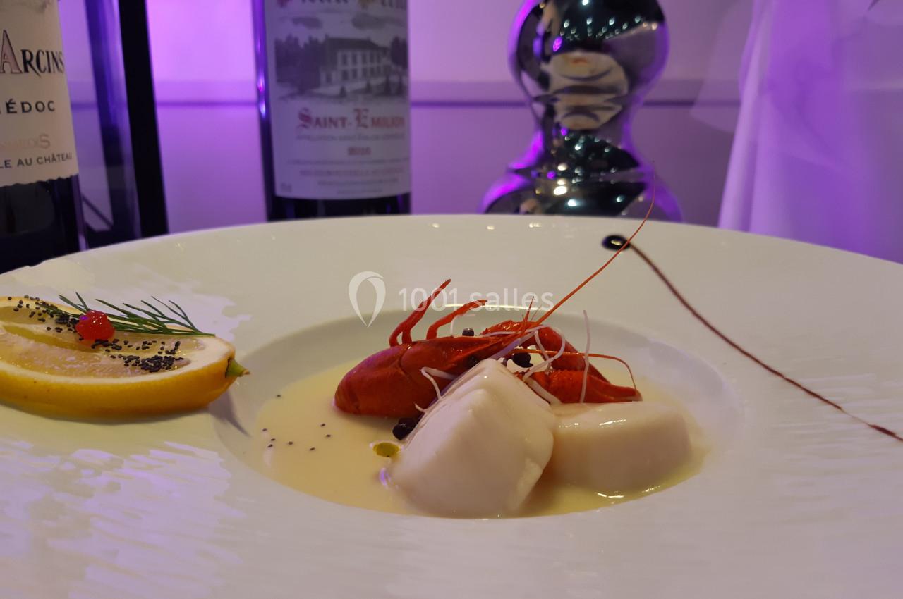 Assiette gastronomique avec noix de Saint-Jacques, langoustine, sauce crémeuse, citron et décoration raffinée.