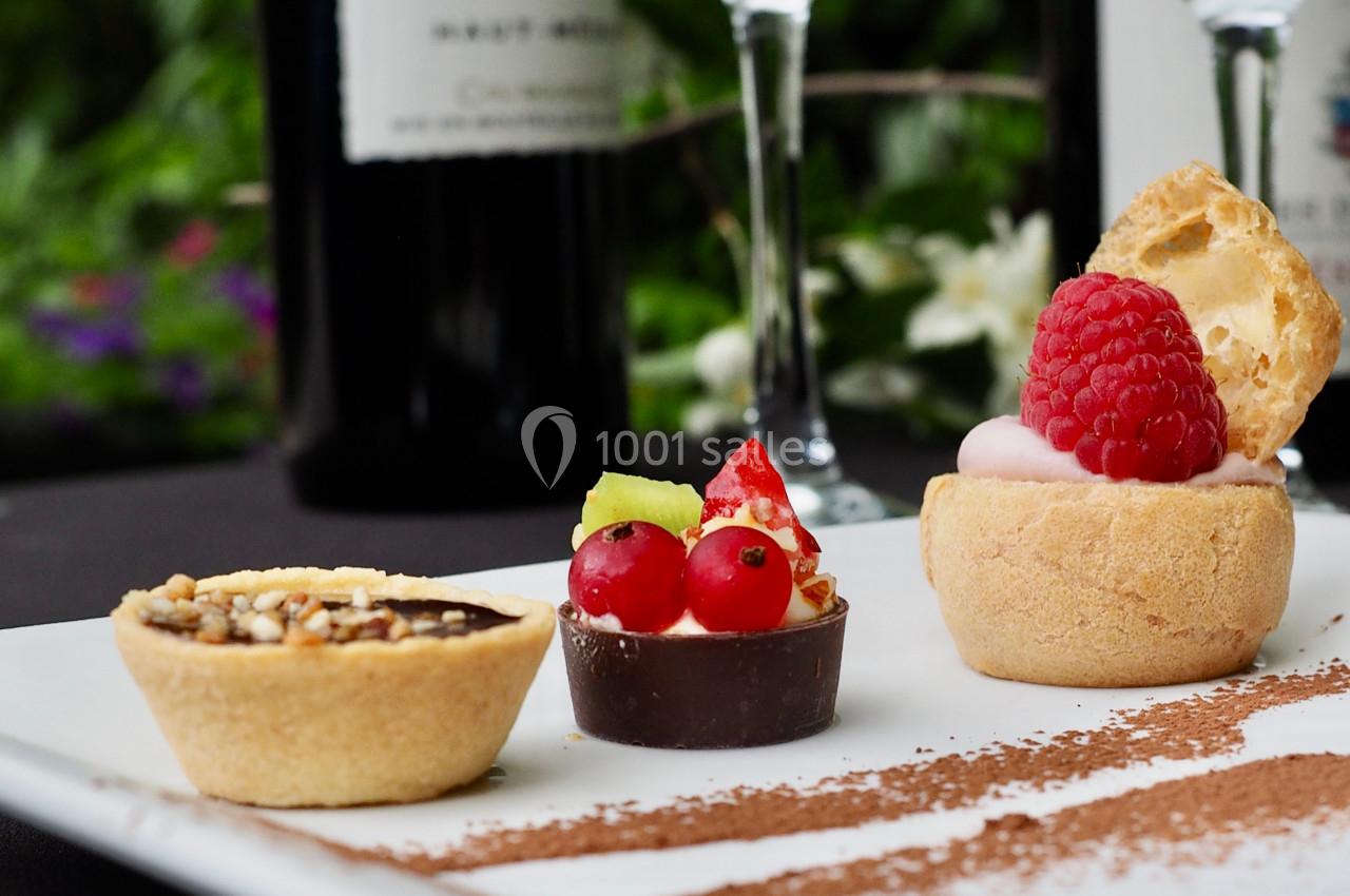 Assortiment de desserts miniatures sur une assiette blanche, décorée de cacao en poudre.