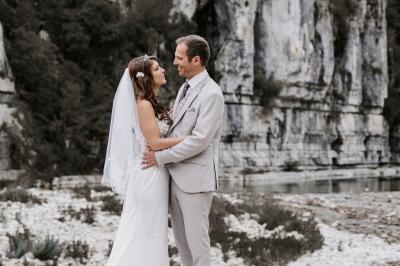 Femme assise, vêtue d'une robe blanche fluide, posant avec une expression sereine sur fond neutre.