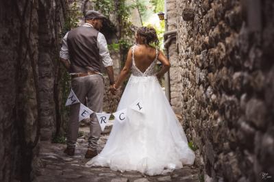 Femme assise, vêtue d'une robe blanche fluide, posant avec une expression sereine sur fond neutre.