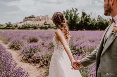 Femme assise, vêtue d'une robe blanche fluide, posant avec une expression sereine sur fond neutre.
