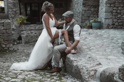Femme assise, vêtue d'une robe blanche fluide, posant avec une expression sereine sur fond neutre.