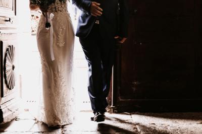 Femme assise, vêtue d'une robe blanche fluide, posant avec une expression sereine sur fond neutre.