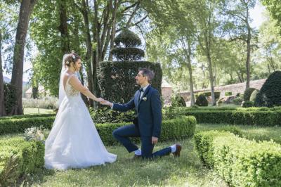 Femme assise, vêtue d'une robe blanche fluide, posant avec une expression sereine sur fond neutre.