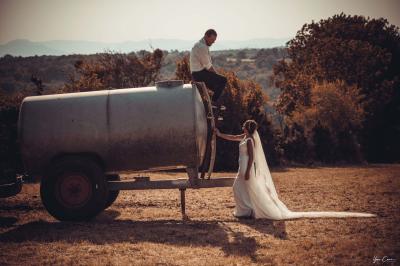 Femme assise, vêtue d'une robe blanche fluide, posant avec une expression sereine sur fond neutre.