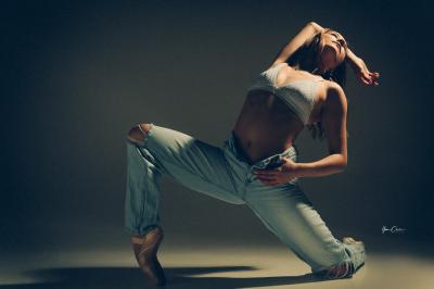 Femme assise, vêtue d'une robe blanche fluide, posant avec une expression sereine sur fond neutre.