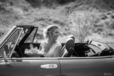 Femme assise, vêtue d'une robe blanche fluide, posant avec une expression sereine sur fond neutre.