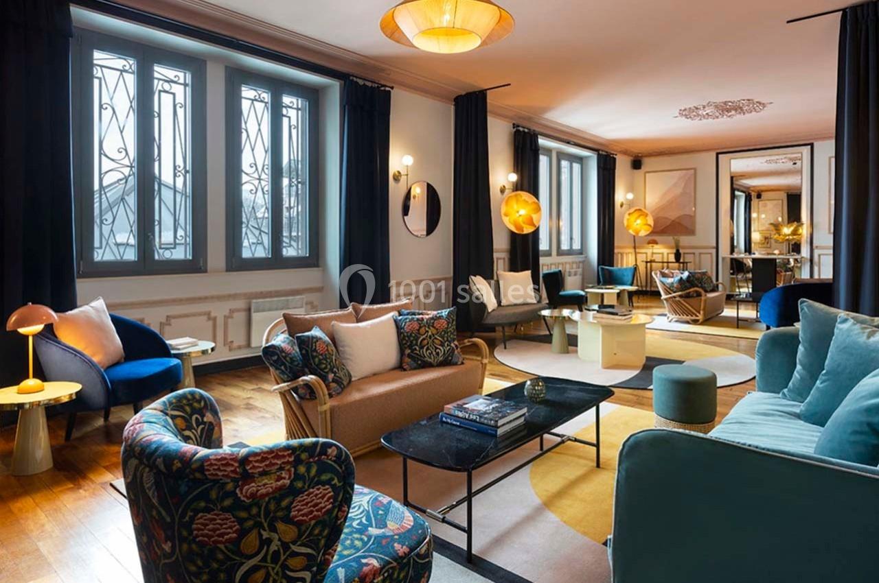 Salon spacieux avec mobilier coloré, grandes fenêtres, lumière naturelle et décoration contemporaine.