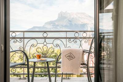 Façade d'un bâtiment éclairé la nuit, entouré d'un jardin avec des arbres, des chaises et des tables en extérieur.