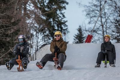 Façade d'un bâtiment éclairé la nuit, entouré d'un jardin avec des arbres, des chaises et des tables en extérieur.
