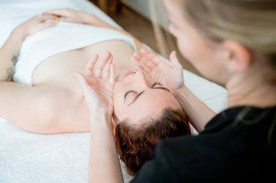 Façade d'un bâtiment éclairé la nuit, entouré d'un jardin avec des arbres, des chaises et des tables en extérieur.