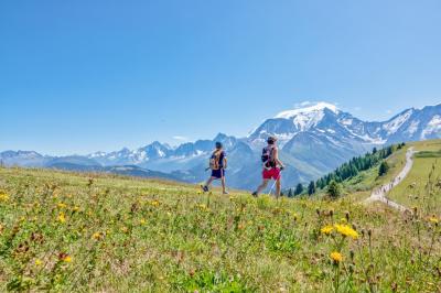 Façade d'un bâtiment éclairé la nuit, entouré d'un jardin avec des arbres, des chaises et des tables en extérieur.