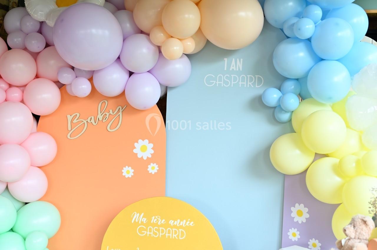 Décoration d'anniversaire avec des ballons pastel et des panneaux personnalisés mentionnant ’1 an Gaspard’.