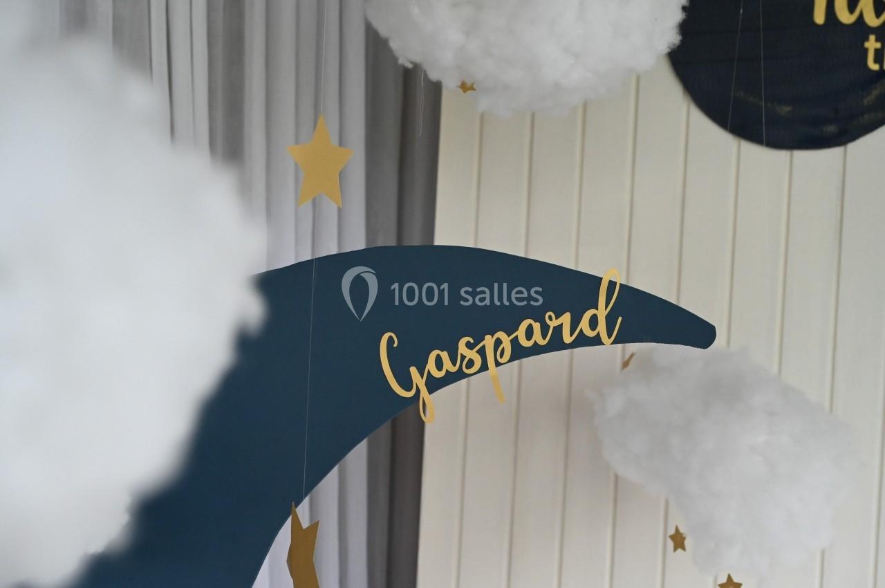 Décoration avec une lune bleue portant le prénom ’Gaspard’, entourée de nuages en coton et d'étoiles dorées.