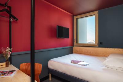 Chambre avec lit double, lits superposés en bois, éclairage chaleureux et mur décoré d'une fresque de paysage naturel.