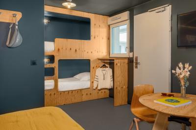 Chambre moderne avec lits superposés en bois, table ronde, chaise, et porte donnant sur l'extérieur.